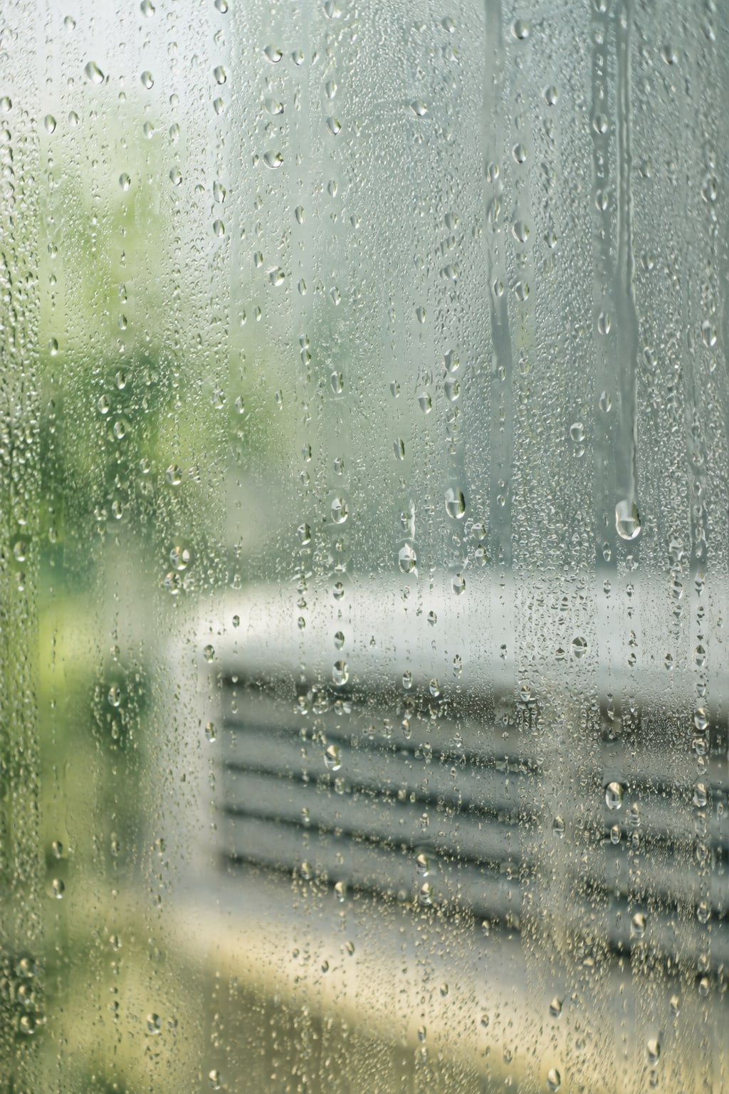 Imagem ilustrativa de gotas de condensação no vidro, com uma saída de ar desfocada ao fundo